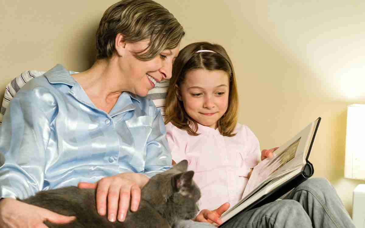 Grandmother, granddaughter and cat looking at photo album