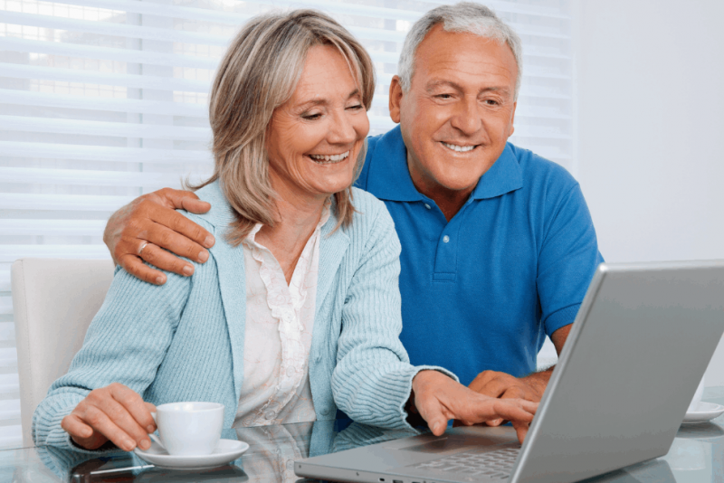a mature man and woman looking at family photos on a laptop