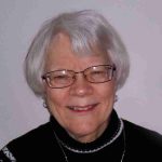 mature woman wearing glasses and smiling at camera